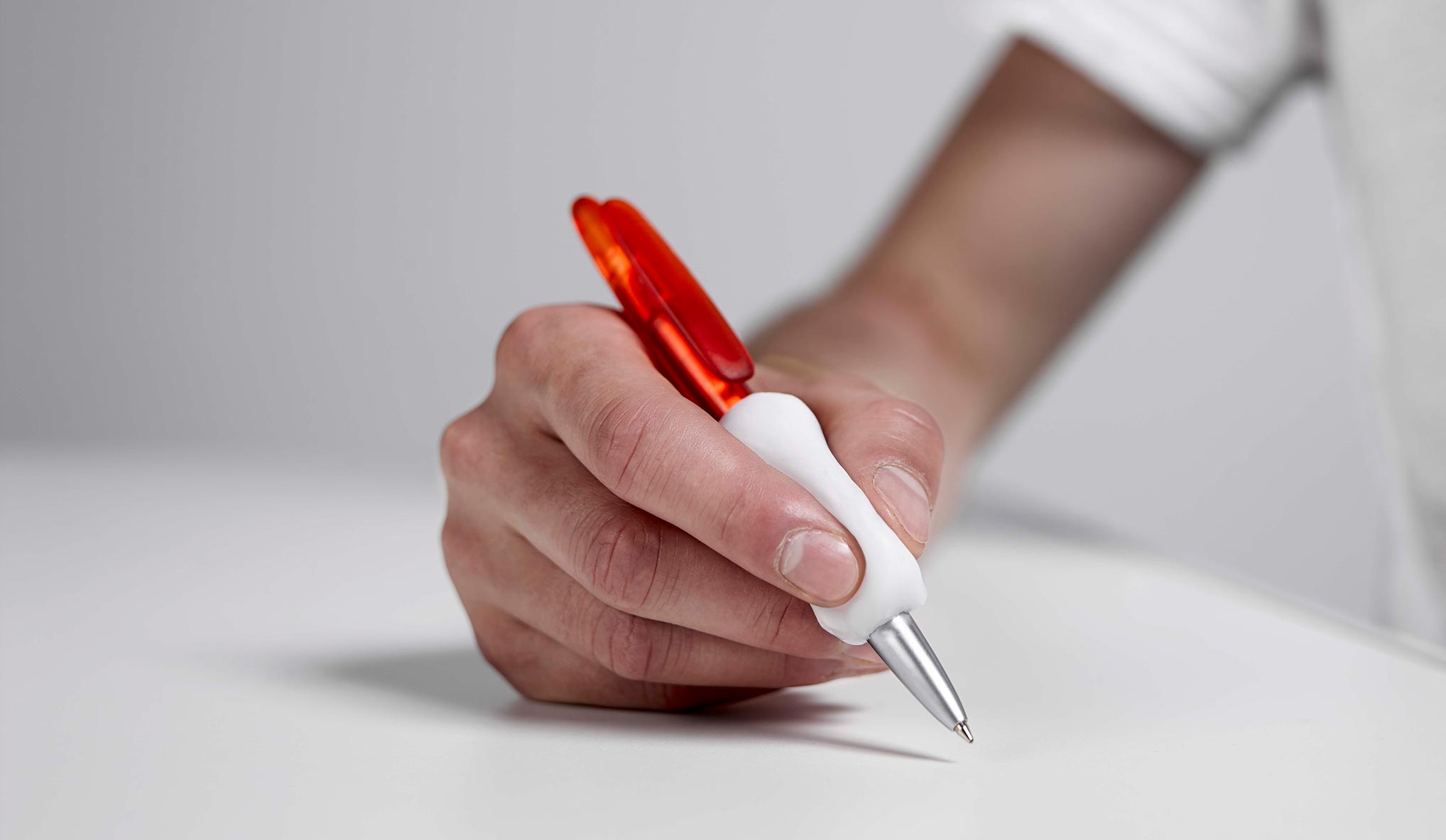 A hand holding a pen with a grip in Allfit.