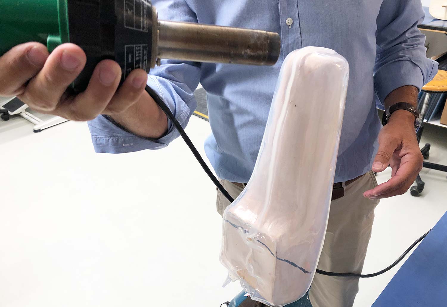 Man using a heat gun to smooth the seam of a drape formed transtibial socket